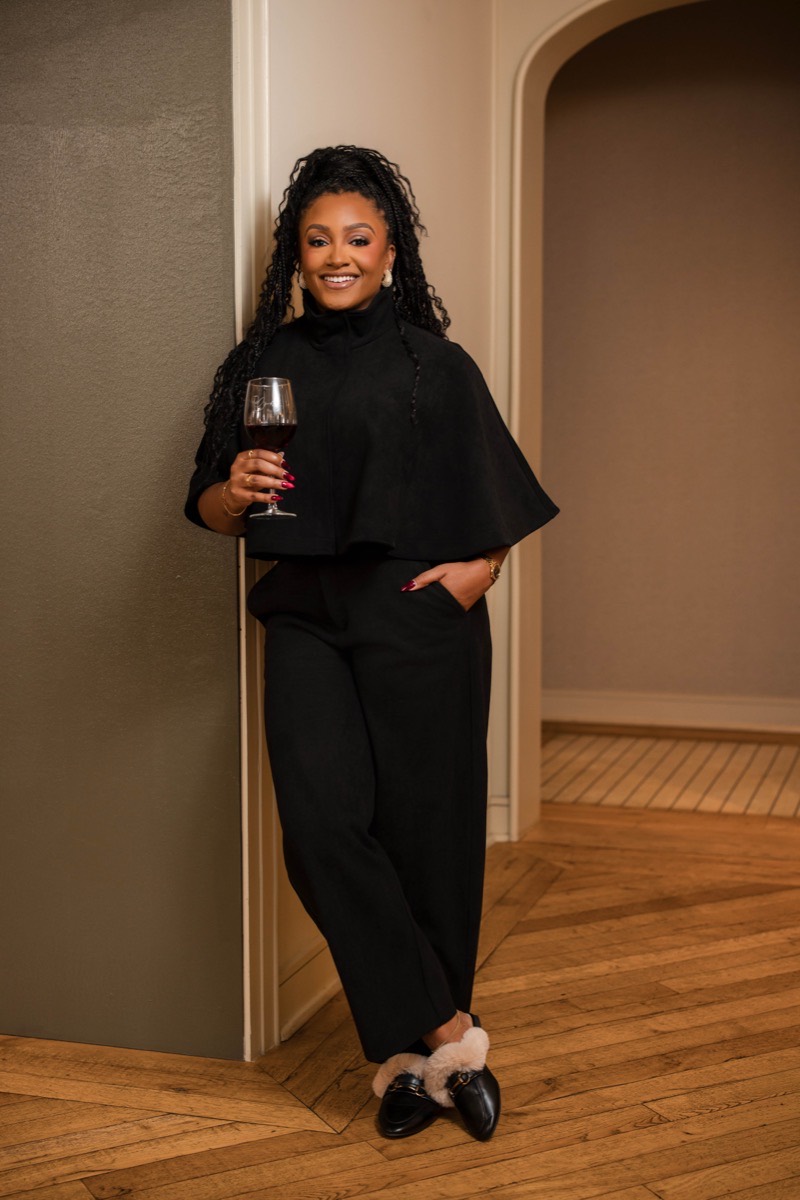 The founder of Cork’d dressed in black, holding a glass of red wine
